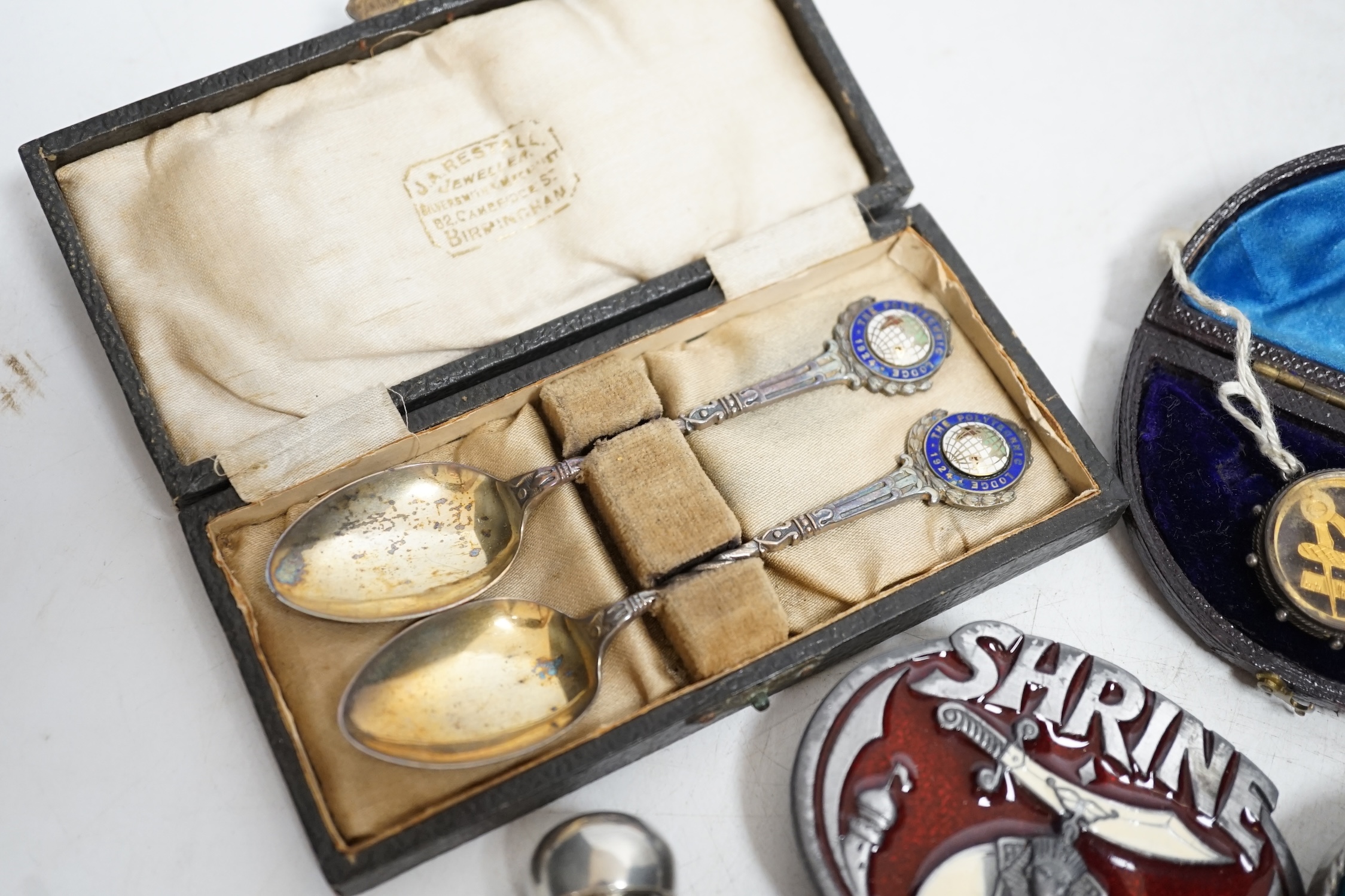 A collection of objects to include a triangular Masonic silver pocket watch, assorted Masonic fobs, enamel buckles, silver presentation spoons and sundries. Condition - varies, mostly fair